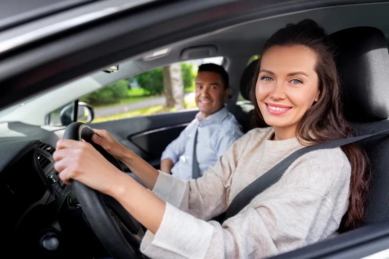 Vrouw toont rijbewijs vanuit auto na geslaagd theorie examen