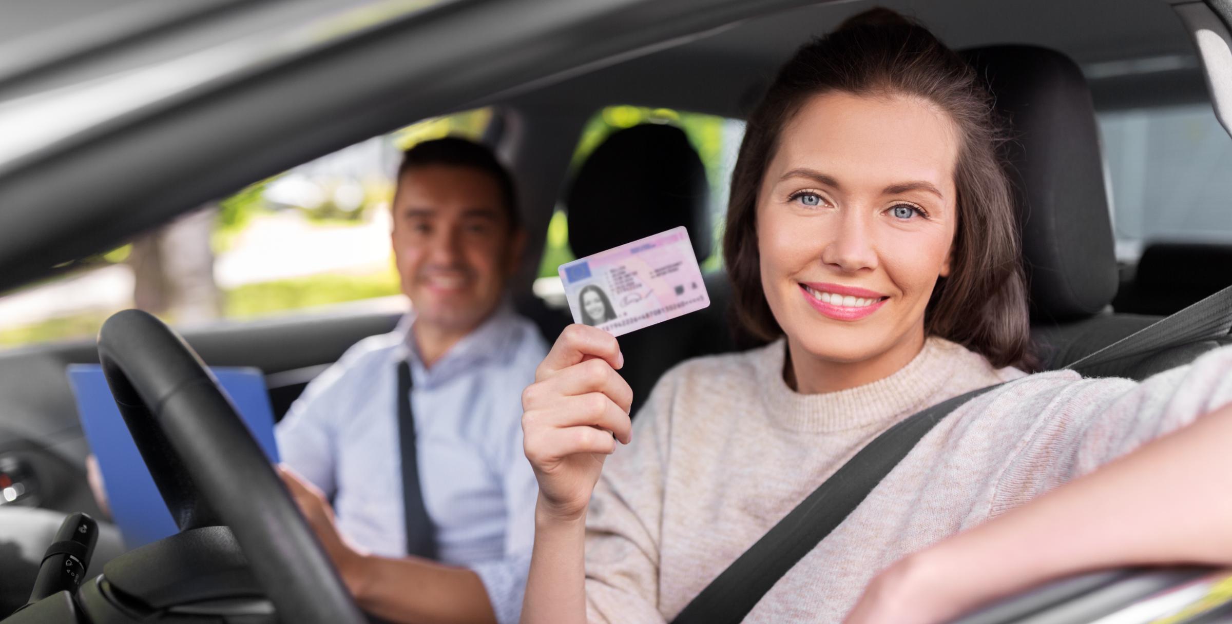 Vrouw toont trots haar rijbewijs vanuit het autoraam na het theorie examen oefenen